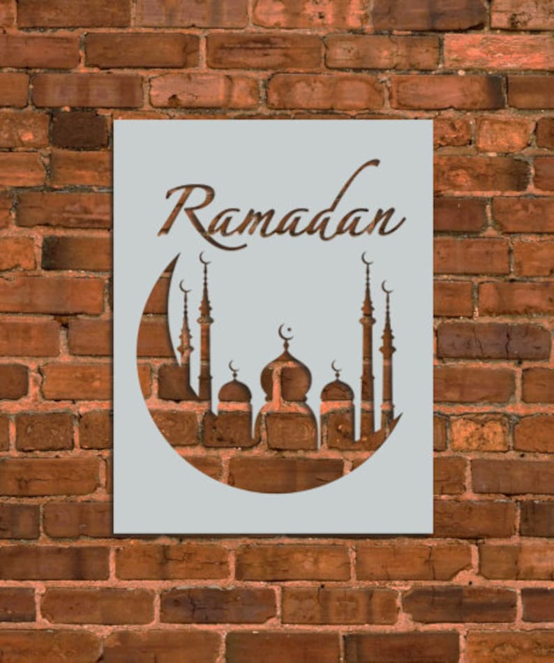 May include: A stencil with the word "Ramadan" and a crescent moon with a mosque silhouette inside. The stencil is on a brick wall background.