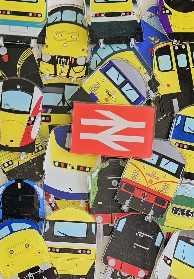 May include: A collection of colorful train-themed stickers featuring various train designs. The stickers include yellow, red, blue, and black trains, with a red and white British Rail logo in the center.