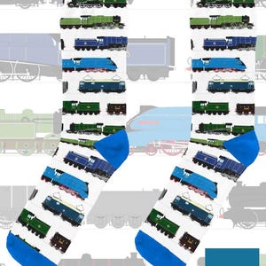May include: White socks with a blue heel and toe, patterned with various train illustrations in green, blue, and brown. The socks feature a variety of train designs, including steam and electric locomotives. The text "On The Rails" is visible in the lower right corner.