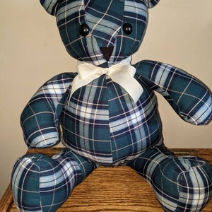 May include: A plush teddy bear made from a green, blue, and white plaid fabric. The bear has a white bow tie and black button eyes.