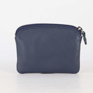 May include: A small, navy blue leather coin purse with a smooth texture and a rounded top edge. The pouch features a matching navy blue zipper closure along the top, complete with a small, rectangular leather pull tab attached to the metal slider.