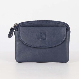 May include: A navy blue leather coin purse featuring a top zipper closure and a front flap pocket with a snap button. The front flap displays a small embossed logo. The purse has a rectangular shape with rounded corners and visible stitching.