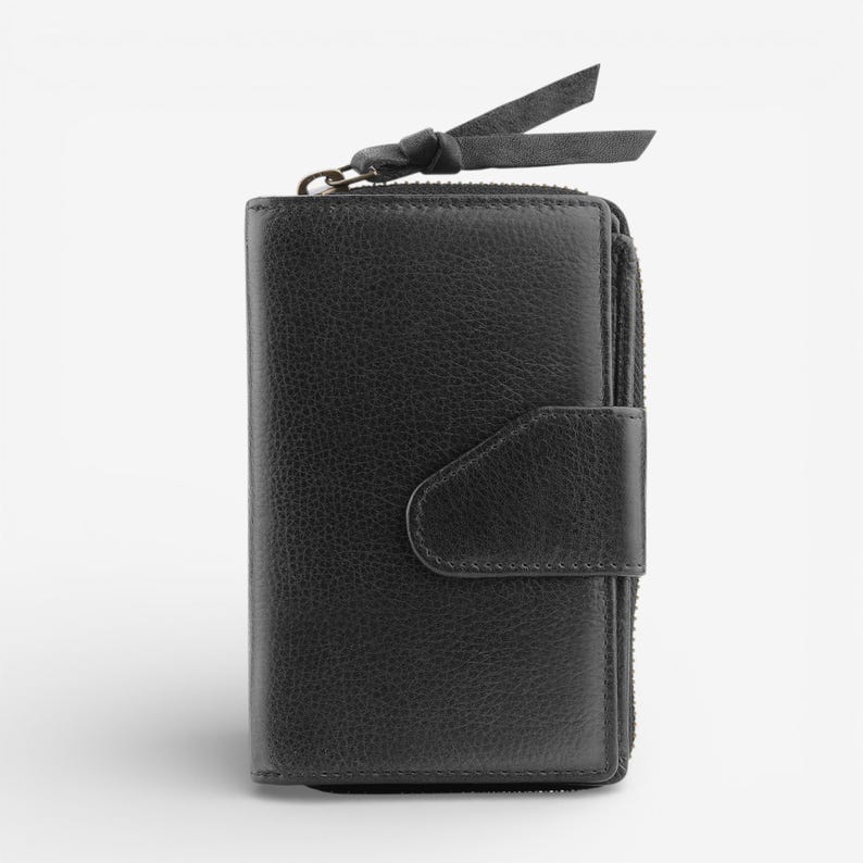 May include: Black leather wallet with a zip closure, a snap fastener, and a small leather strap with a knot. The wallet has a textured surface and a classic design.
