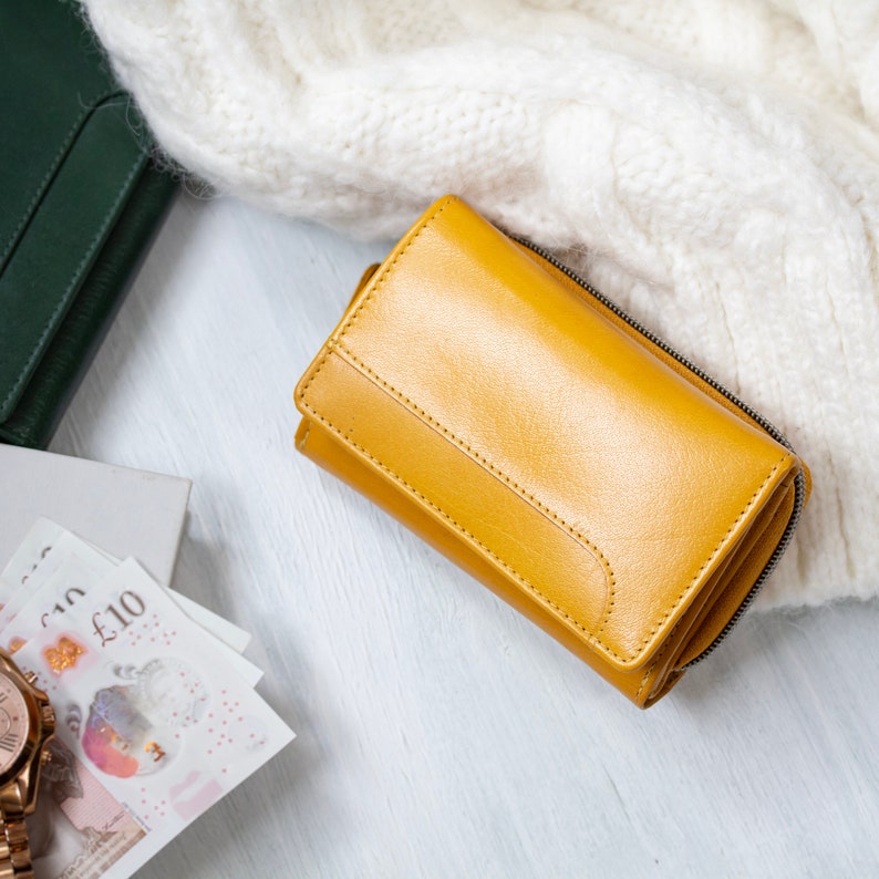 Soft leather purse in yellow on a white knit fabric with notes and a watch nearby. This ladies wallet is perfect as a unique gift for her or a gift for wife.