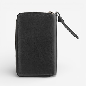 May include: A black leather wallet with a zip closure and a small leather pull tab. The wallet is rectangular and has a textured surface.