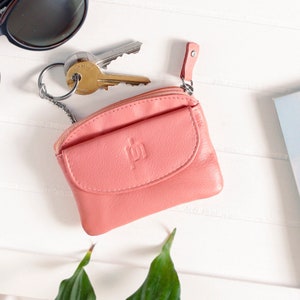 a coral-pink leather coin pouch with a keyring attached to it.