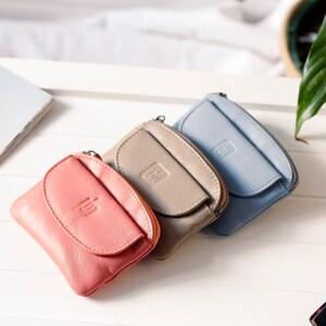 three leather purses on a table. There is a variety of colours, coral, beige and blue.