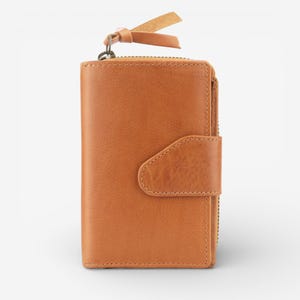 May include: A tan leather wallet with a zip and snap closure. The wallet has a small leather pull tab attached to the zip and a leather strap. The wallet is made of smooth leather. The wallet is a light brown colour.