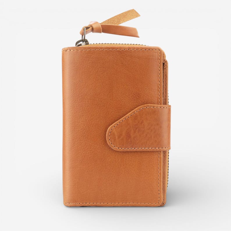 May include: A tan leather wallet with a zip and snap closure. The wallet has a small leather pull tab attached to the zip and a leather strap. The wallet is made of smooth leather. The wallet is a light brown colour.
