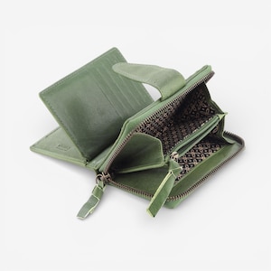 May include: Open green leather wallet with multiple compartments, including card slots and a zipped coin pouch. The wallet features a textured exterior and a patterned interior lining. The zip pulls are made of matching green leather.