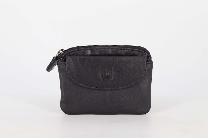 May include: A small black leather coin purse featuring a top zipper closure and a front pocket with a flap. The front of the purse displays a small embossed square logo. The design is compact with rounded corners and a smooth, matte finish.