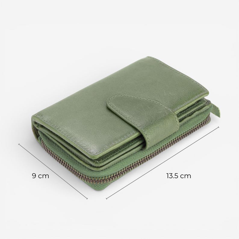 May include: A sage green leather wallet with a zip-around closure and a snap closure. The wallet measures 13.5 cm long and 9 cm wide. The wallet has a textured appearance and a visible zipper.