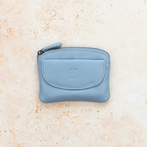 a light blue leather coin purse with a zippered section which has a zipper puller and a front pocket.