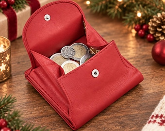 May include: A red leather coin purse with a snap button closure, shown in an open position. The interior of the purse contains several metallic coins of varying sizes. The purse features a smooth texture and a structured, folding design.