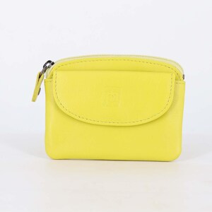 May include: A bright lime yellow coin purse featuring a smooth exterior, a top zipper closure with a matching pull tab, and a front flap pocket with a subtle embossed logo detail. The rectangular pouch has rounded corners and a compact design.