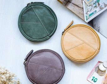 May include: Three round leather coin purses with zipper closures. The purses are in green, brown, and tan.