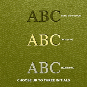 May include: Close-up of a textured, olive-green surface with three sets of the letters "ABC" in different styles. The top set is blind, the middle set is gold foil, and the bottom set is silver foil. Text at the bottom reads "CHOOSE UP TO THREE INITIALS."