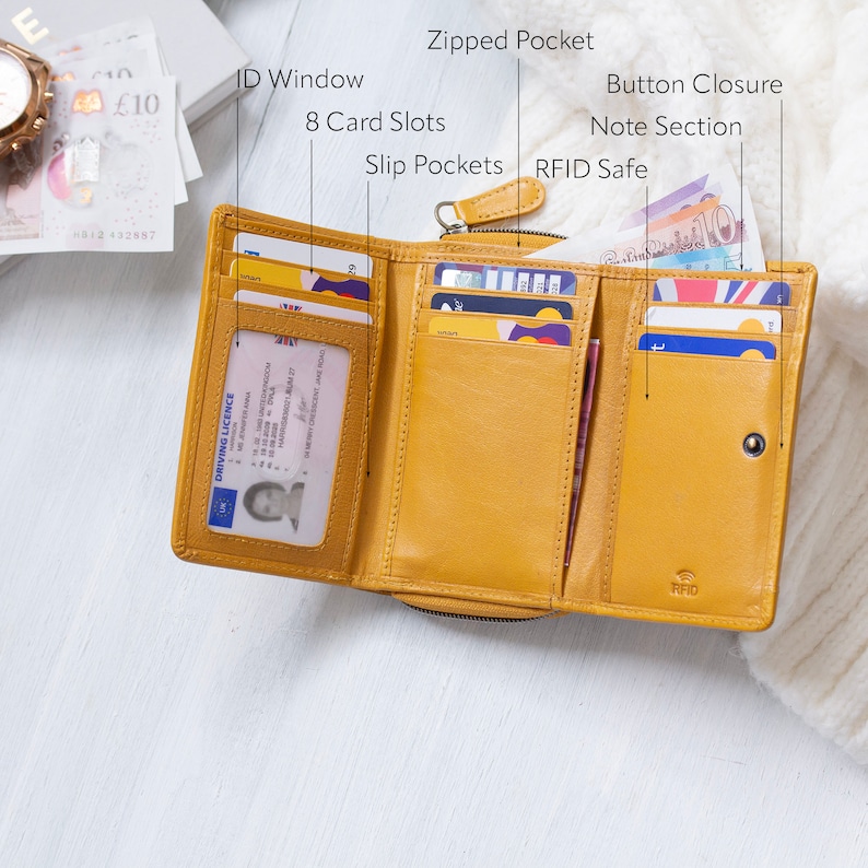 Open soft leather purse in yellow showing various features including an ID window, 8 card slots, slip pockets, a zipped pocket, a button closure, note section, and RFID safe compartment. This wallet for women is ideal as a gift for her.