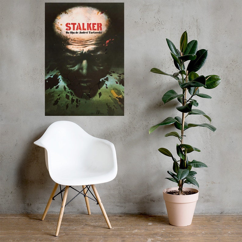 May include: A vintage movie poster for the film "STALKER" by Andrei Tarkovsky. The poster features a close-up of a man's face with a distressed, textured background.