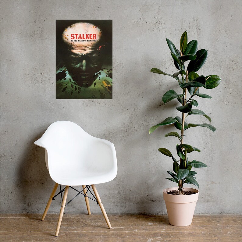 May include: A vintage movie poster for the film "STALKER" by Andrei Tarkovsky. The poster features a close-up of a man's face with a dark, mysterious background.
