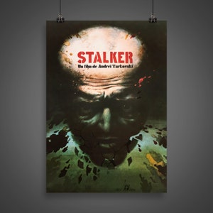 May include: A vintage movie poster for the film "STALKER" by Andrei Tarkovsky. The poster features a close-up of a man's face with a cracked, green and brown background. The title "STALKER" is in red letters.