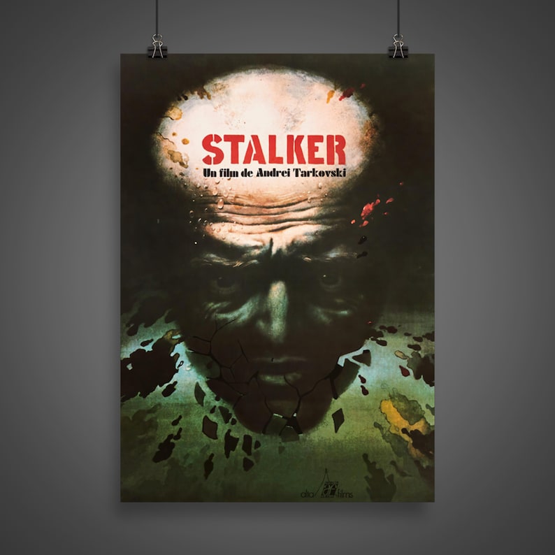 May include: A vintage movie poster for the film "STALKER" by Andrei Tarkovsky. The poster features a close-up of a man's face with a cracked, green and brown background. The title "STALKER" is in red letters.
