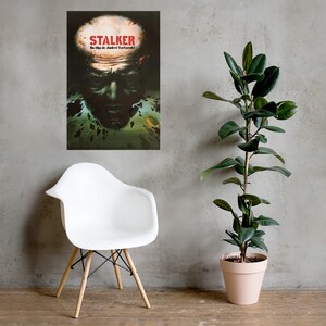 May include: A vintage movie poster for the film "STALKER" directed by Andrei Tarkovsky. The poster features a close-up of a man's face with a green and brown background.