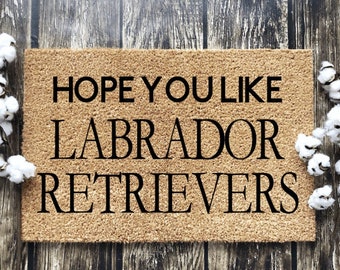 May include: A brown coir doormat with the text "HOPE YOU LIKE LABRADOR RETRIEVERS" in black lettering.
