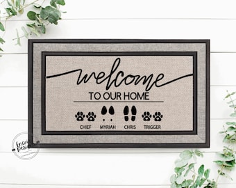 May include: A welcome mat with a black border and a beige background. The text "welcome to our home" is printed in black cursive script. Below the text are four sets of footprints, two paw prints, two human footprints, and the names "Chief", "Myriah", "Chris", and "Trigger" printed below each set of footprints.