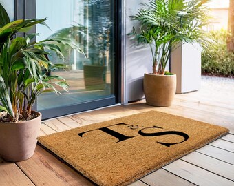 May include: A brown coir doormat with the letters "T & S" in black lettering.