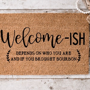 May include: Welcome-ish doormat with the text "Depends on who you are and if you brought bourbon" on a brown background.