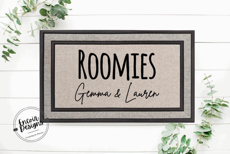 May include: A brown doormat with a black border and the text "ROOMIES Gemma & Lauren" in black.