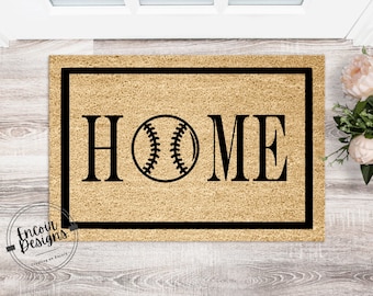 Może przedstawiać: Brązowa mata kokosowa z czarną ramką i napisem "HOME" czarnymi literami. Grafika przedstawiająca piłkę baseballową znajduje się na środku między literami "H" i "M".