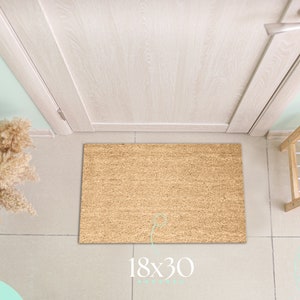 May include: A rectangular doormat made of natural fibers, measuring 18 x 30 inches, lies in front of a white door. The mat has a textured surface and is surrounded by light-colored flooring. A shoe rack and shoes are visible.