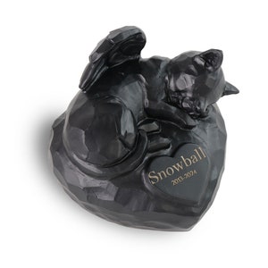 Può includere: Figurina commemorativa di gatto nero con ali, che dorme su una roccia a forma di cuore con l'iscrizione "Snowball 2013-2024".
