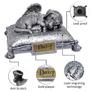 May include: Silver pet urn shaped like a sleeping dog with angel wings, resting on a pillow. The urn has a gold plaque with the name "Daisy" and the dates "2003-2022". The urn is engraved with the text "If love could have saved you, you would have lived forever."