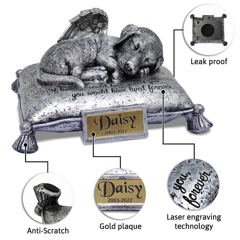 May include: Silver pet urn shaped like a sleeping dog with angel wings, resting on a pillow. The urn has a gold plaque with the name "Daisy" and the dates "2003-2022". The urn is engraved with the text "If love could have saved you, you would have lived forever."