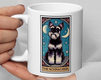 Puede incluir: Taza de cerámica blanca con una ilustración de perro Schnauzer. El diseño incluye un fondo azul con estrellas y lunas crecientes, enmarcado por un borde decorativo. El texto "THE SCHNAUZER" está en la parte inferior.