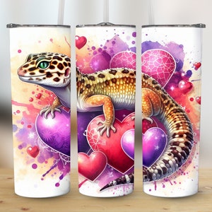 May include: A white stainless steel tumbler with a colorful watercolor design featuring a gecko lizard on a heart. The background is a mix of pink, purple, and yellow with hearts and sparkles.