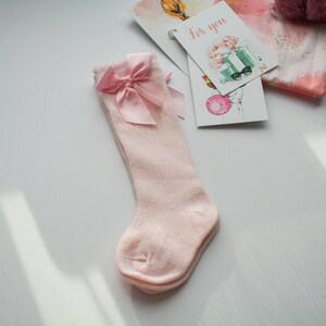 Peut inclure: Chaussettes roses &agrave; hauteur du genou avec un n&oelig;ud en satin rose sur le dessus.