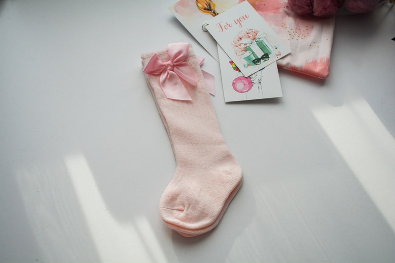Peut inclure: Chaussettes roses &agrave; hauteur du genou avec un n&oelig;ud en satin rose sur le dessus.