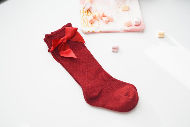 Peut inclure: Chaussettes rouges montant au genou avec un n&oelig;ud en satin rouge sur le dessus.