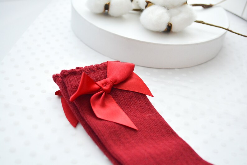 Peut inclure: Chaussettes rouges montant au genou avec un grand n&oelig;ud en satin rouge.
