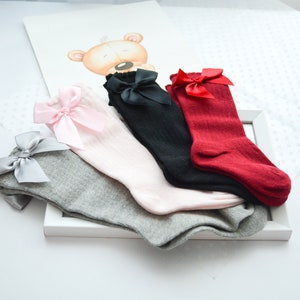 Peut inclure: Quatre paires de chaussettes hautes avec des n&oelig;uds. Les chaussettes sont en gris, rose, noir et rouge.