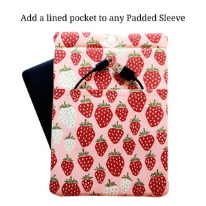 May include: A pink padded sleeve with a strawberry print. The sleeve has a lined pocket on the front, with a black charging cable plugged into a device inside the pocket.