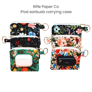 May include: Several floral-patterned iPod earbuds carrying cases. The cases have a zippered closure, a gold-colored ring, and a variety of floral designs in colors like black, blue, and red. One case contains white earbuds, and another contains a black device.
