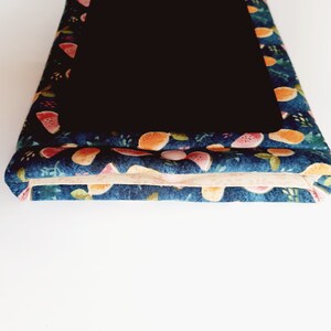 May include: A navy blue fabric case with a black interior. The case is decorated with a colorful pattern of watermelon and orange slices. A pink button secures the case closed. The case is likely for a tablet or e-reader.
