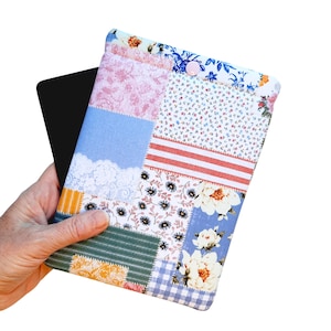 May include: A patchwork tablet case with a variety of floral and patterned fabrics in pink, blue, white, and orange. The case has a button closure and is holding a black tablet.