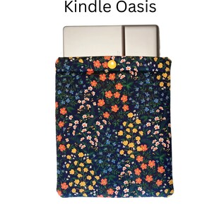 May include: A Kindle Oasis case featuring a navy blue floral design. The fabric case has a yellow button fastening. The words "Kindle Oasis" are printed above the case.