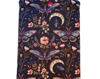 May include: A rectangular fabric sleeve for an e-reader featuring a dark navy background with a repeating pattern of colorful moths, pink flowers, green stems, and crescent moons. A small pink snap button secures the top flap of the protective case.